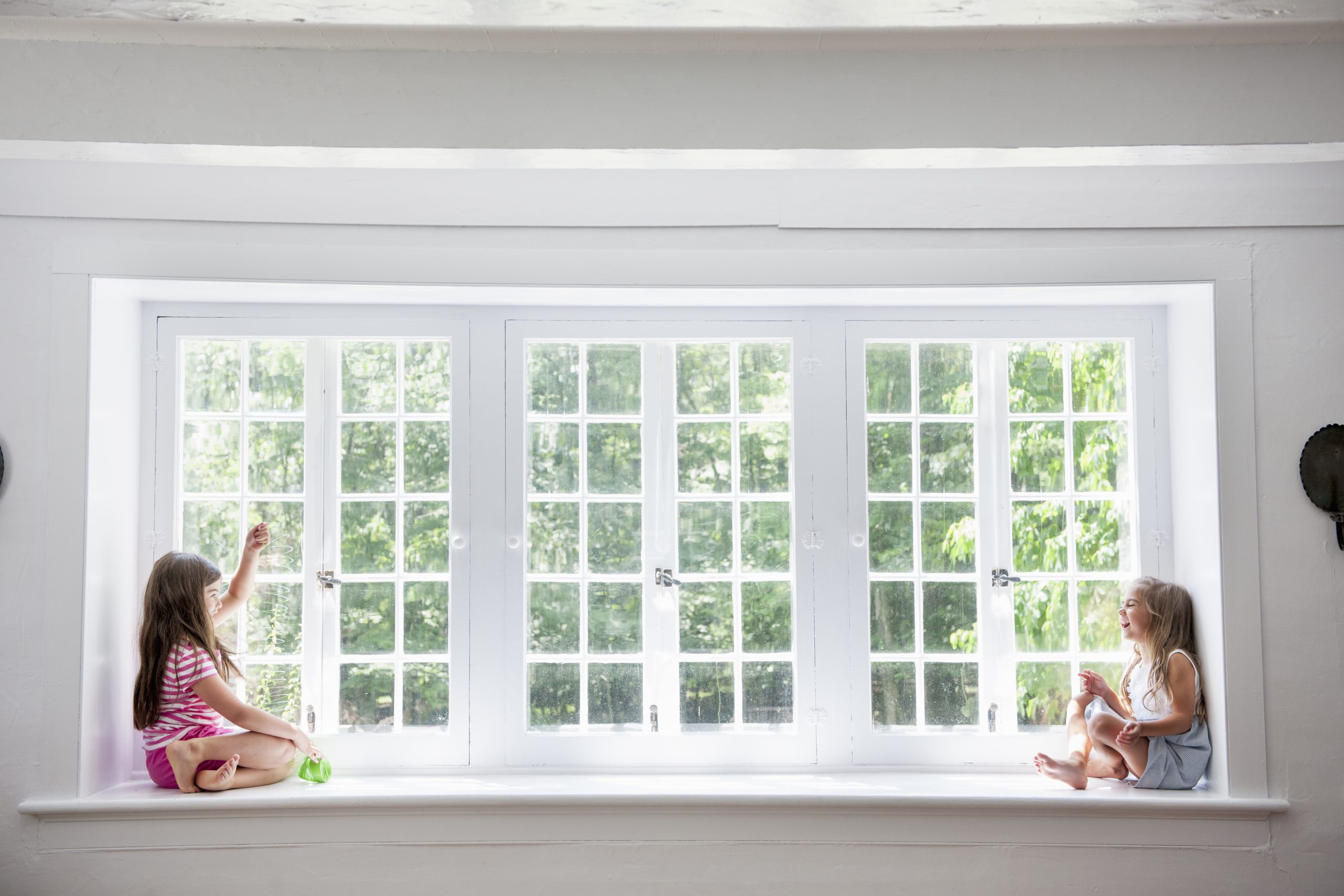 Two young children on either side of a very long white window.